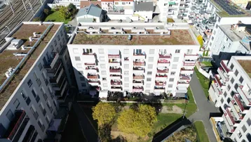 Luftaufnahme einer modernen Wohnanlage mit begrünten Dächern und Innenhöfen.