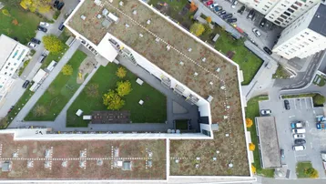 Luftaufnahme des Wohnkomplexes mit begrüntem Flachdach, Innenhof und Spielplatz.