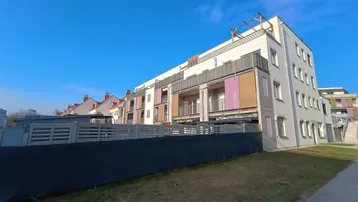 Moderne Wohnanlage mit farbigen Balkonen und gepflegten Grünflächen in städtischer Umgebung.
