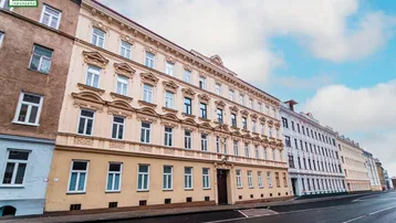 Historisches Mehrfamilienhaus mit reich verzierter Fassade an einer städtischen Straße.