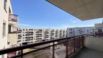 Balkon mit Blick auf gegenüberliegende Wohngebäude und den blauen Himmel.
