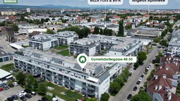 Luftaufnahme der Wohnanlage mit Markierungen für nahegelegene Einkaufsmöglichkeiten und Apotheke.