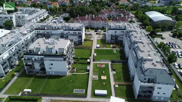 Luftaufnahme des Wohnkomplexes mit großzügigen Grünflächen und Spielplatz im Innenhof.