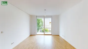 Heller Raum mit Parkettboden und Zugang zu einem französischen Balkon, bietet viel Tageslicht.