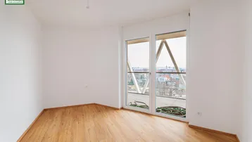 Leeres Schlafzimmer mit Holzboden und großen Fenstern, die einen weiten Blick bieten.