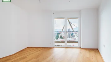 Heller Raum mit Parkettboden und großem Fenster, das einen weiten Blick bietet.