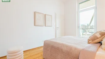 Helles Schlafzimmer mit großem Fenster und Zugang zu einem französischen Balkon.