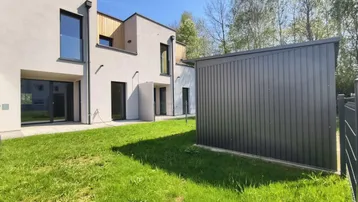 Hinterhofbereich der modernen Reihenhäuser mit Rasenfläche und einem praktischen Gartenschuppen.