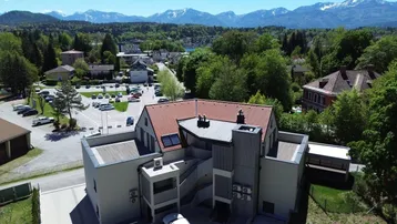 Luftaufnahme einer modernen Wohnanlage mit Bergblick und umliegender Infrastruktur.