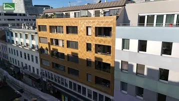 Luftaufnahme der modernen Gebäudefassade mit einzigartiger goldener Verkleidung und umliegenden Gebäuden in der Stadt.
