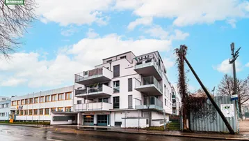 Moderne Wohnanlage mit mehreren Balkonen und zeitgenössischer Architektur an einer Straße gelegen.