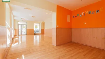 Heller, offener Raum mit Holzpaneelen und Laminatboden, ideal für kreative Aktivitäten.