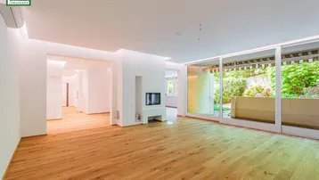 Geräumiges, helles Wohnzimmer mit modernem Kamin, Holzboden und Zugang zu einer grünen Terrasse.