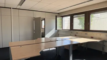 Geräumiges Büro mit mehreren Arbeitsplätzen, großen Fenstern und viel Tageslicht, ausgestattet mit Einbauschränken.