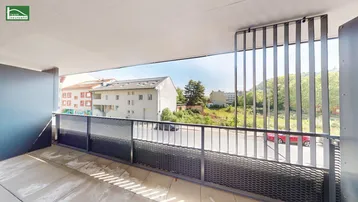 Geräumiger Balkon mit moderner Metallbrüstung und Blick auf die umliegenden Gebäude und Grünflächen.