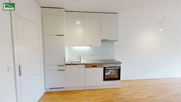 Kompakte, moderne Küchenzeile mit weißen Schränken und integrierten Geräten in hellem Raum.