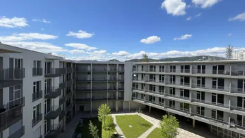 Panoramablick auf den weitläufigen Innenhof des Wohnkomplexes mit grünen Flächen und umliegenden Gebäuden.