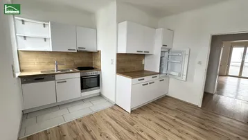 Moderne Küche mit weißen Schränken, Holzarbeitsplatten und integrierten Geräten, offen zum Wohnbereich.