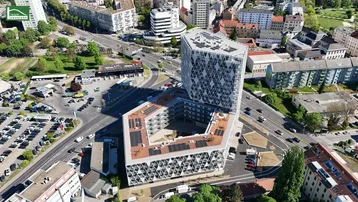 Moderne Gebäudekomplex-Architektur aus der Vogelperspektive in städtischer Umgebung mit umliegenden Straßen und Parkplätzen.