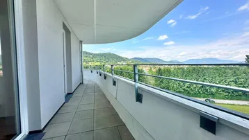 Langer, geschwungener Balkon mit Fliesenboden und weitem Blick auf grüne Hügel und die Umgebung.