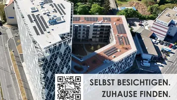 Luftaufnahme eines modernen Gebäudekomplexes mit Photovoltaikanlage und begrüntem Innenhof.