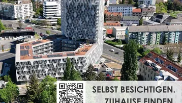 Luftaufnahme eines modernen Neubaus mit markanter Architektur und städtischem Umfeld.