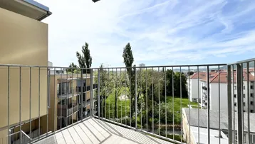 Geräumiger Balkon mit Metallgeländer und Blick auf grüne Bäume und die Umgebung.