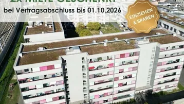 Luftaufnahme eines modernen Wohngebäudes mit begrüntem Flachdach und zahlreichen Balkonen in städtischer Umgebung.
