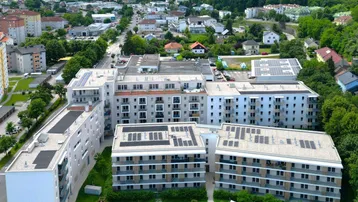 Luftaufnahme eines modernen Wohnkomplexes mit mehreren Gebäuden und Grünflächen.