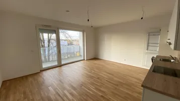 Lichtdurchfluteter Wohnbereich mit großem Fenster und Zugang zum Balkon, ideal für entspannte Stunden.