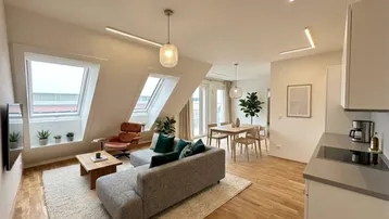 Helles, modern eingerichtetes Wohn-Esszimmer mit offener Küche, Dachschrägen und großen Dachfenstern.