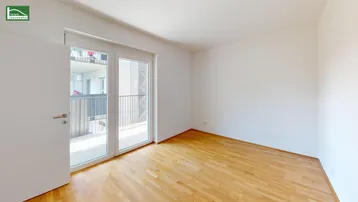 Helles, leeres Zimmer mit Holzboden und Zugang zu einem Balkon, bereit zur individuellen Gestaltung.