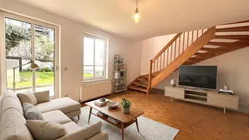Virtuell inszeniertes Wohnzimmer mit Holztreppe, Parkettboden und Zugang zum Gartenbereich.
