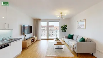 Helles Wohnzimmer mit offener Küchenzeile, Parkettboden und Zugang zu einem Außenbereich.
