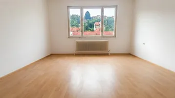 Helles Zimmer mit Laminatboden, weiß gestrichenen Wänden und Blick ins Grüne.