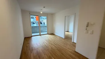 Helles Zimmer mit Parkettboden und Zugang zu einem Balkon, ideal als Wohnbereich nutzbar.