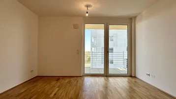 Helles Zimmer mit Parkettboden und Zugang zu einem Balkon, bereit zur individuellen Gestaltung.