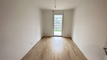 Leeres Schlafzimmer mit Holzboden und Zugang zu einem französischen Balkon.