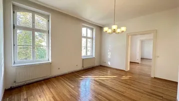 Helles Wohnzimmer in einem Altbau mit hohen Decken, großen Fenstern und schönem Parkettboden.