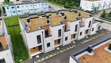 Moderne Reihenhäuser mit Gründächern und Holzfassadenelementen in einer Wohnsiedlung.