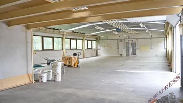 Großer, leerer Gewerberaum mit Betonboden, hohen Decken und vielen Fenstern, bereit für den Ausbau.