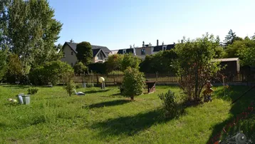 Gepflegter Gartenbereich mit Rasenfläche, Bäumen und Blick auf benachbarte Häuser.