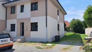 Neubau-Doppelhaushälfte mit beiger und weißer Fassade, großen Fenstern und kleinem Vorgarten.