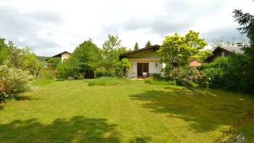 Großzügiger Gartenbereich mit Rasenfläche und Blick auf das Einfamilienhaus mit Terrasse.