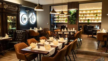 Gemütlicher Restaurantbereich mit Holzböden, dunklen Möbeln und stimmungsvoller Beleuchtung, inklusive einer Pflanzenwand.
