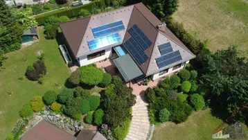 Luftaufnahme eines Einfamilienhauses mit Solaranlagen auf dem Dach und gepflegtem Gartenbereich.