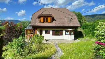 Charmantes Einfamilienhaus mit Mansarddach und gepflegtem Vorgarten in grüner Umgebung.