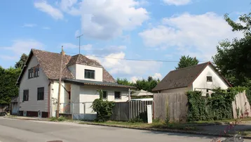 Zwei Wohnhäuser mit Satteldächern und einem Holzzaun an einer ruhigen Straße.