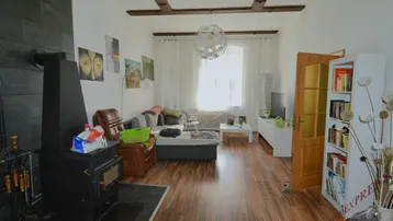 Gemütliches Wohnzimmer mit Holzbalken, Kaminofen und Laminatboden, hell und einladend.