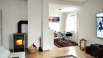 Gemütlicher Wohnbereich mit Kaminofen und offenem Übergang zum Essbereich mit Holzboden.
